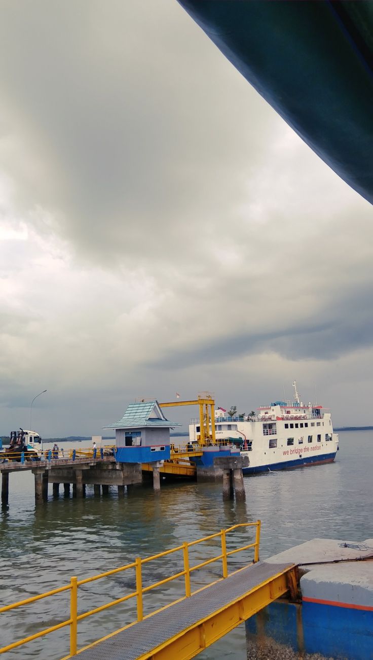 boats are docked in the water near a dock with yellow railings and blue steps