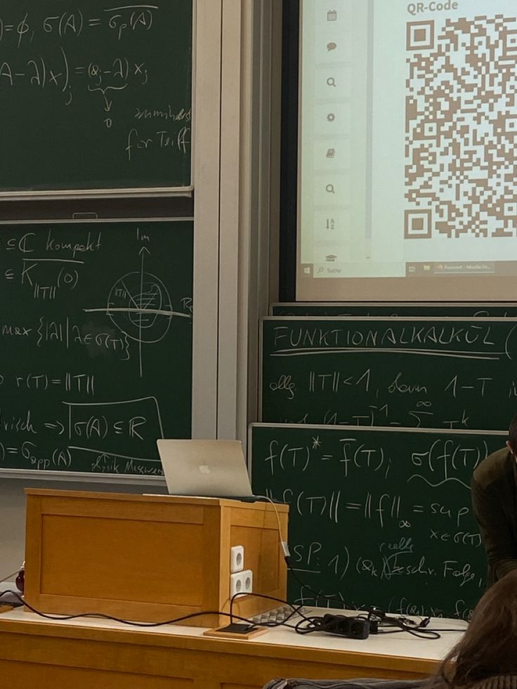 a man sitting at a desk in front of a blackboard with qr code on it