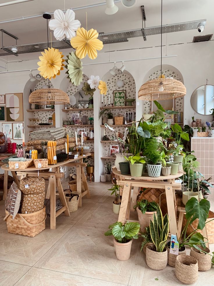 a room filled with lots of potted plants and hanging baskets on the wall next to each other