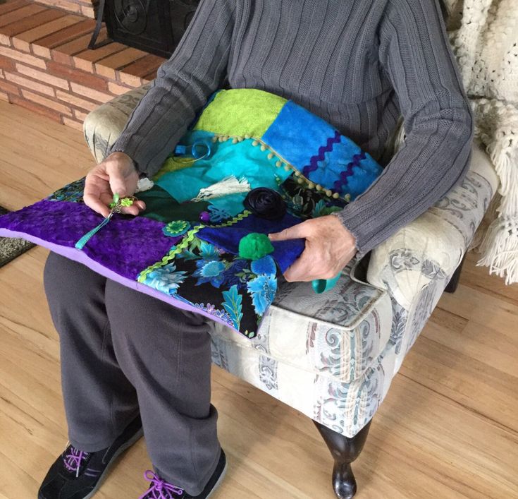 an older woman sitting in a chair holding a piece of fabric on top of it