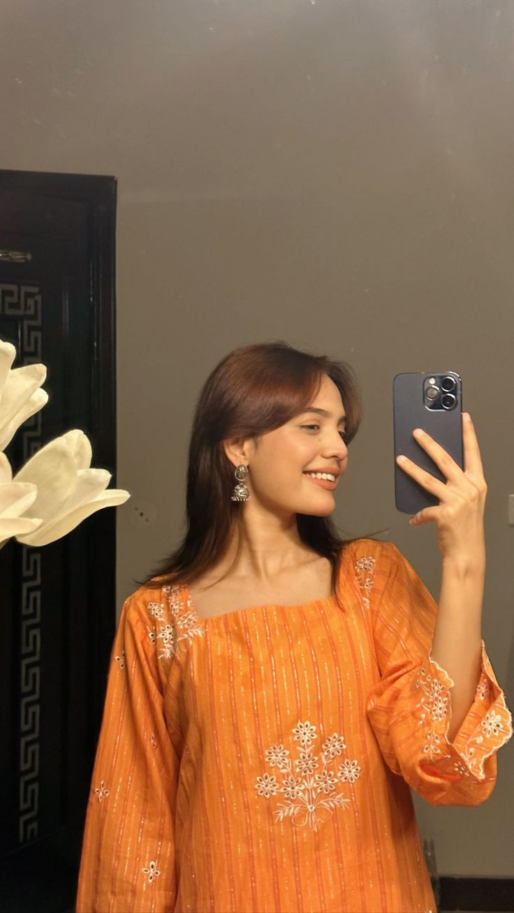 a woman taking a selfie with her cell phone in front of a flower arrangement