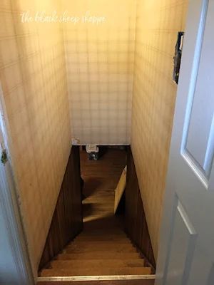 an open door leading to a hallway with wooden steps and tiled walls in the background