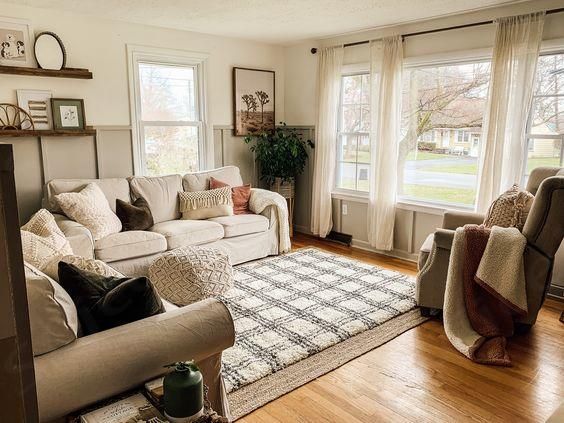 a living room with couches, chairs and rugs in front of two windows