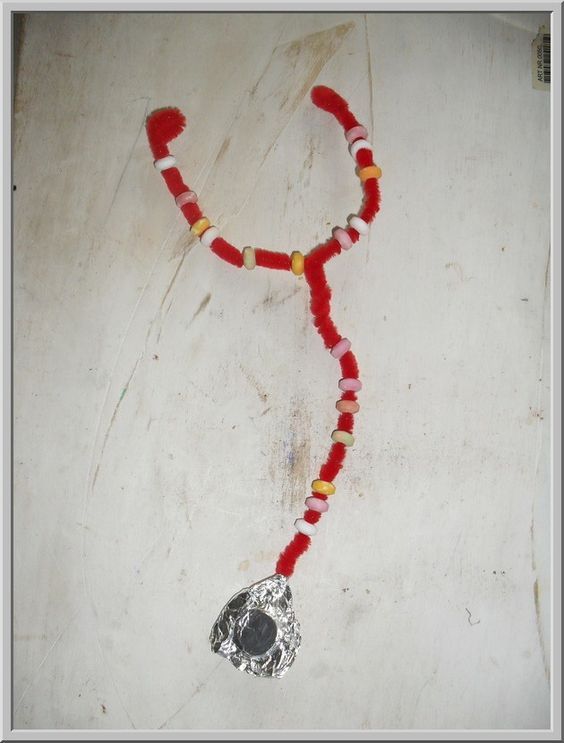 a red and white beaded necklace with a silver metal pendant on it's end