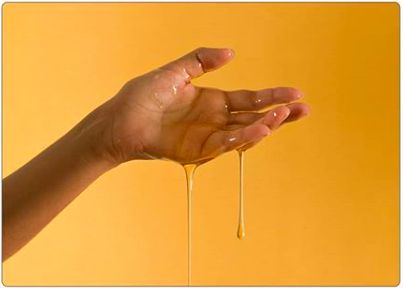 a hand is holding some liquid on a yellow background and it looks like they are dripping