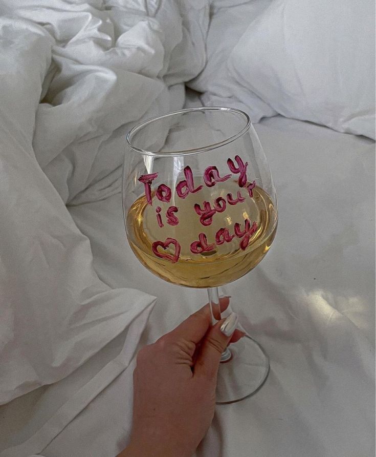 a person holding a wine glass with the words today is your day written on it