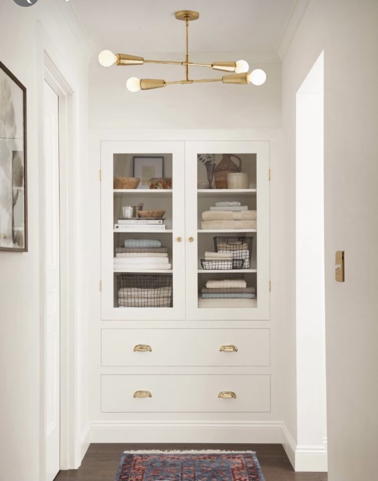 an empty hallway with white cabinets and gold fixtures on the wall, along with a blue rug