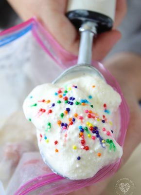 a person holding a scoop of ice cream with sprinkles