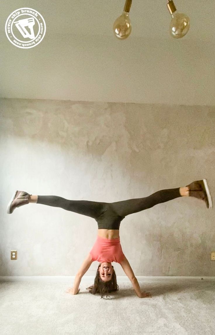 a woman is doing a handstand on the floor with her legs spread out