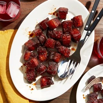 two plates filled with food next to glasses of juice and silverware on a wooden table