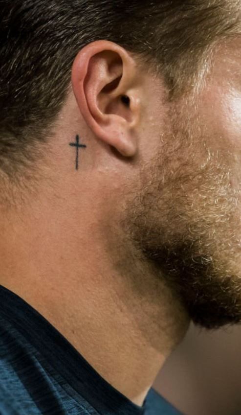 a man with a cross tattoo on his ear