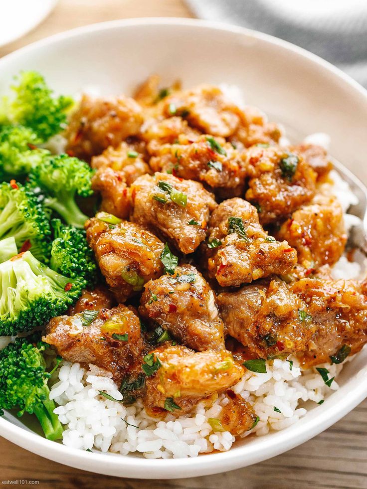 a white bowl filled with rice and meat next to broccoli