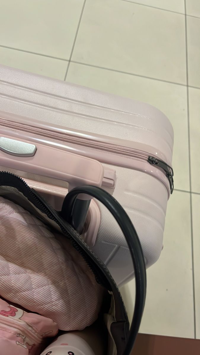 a piece of pink luggage sitting on top of a floor next to a white tile wall