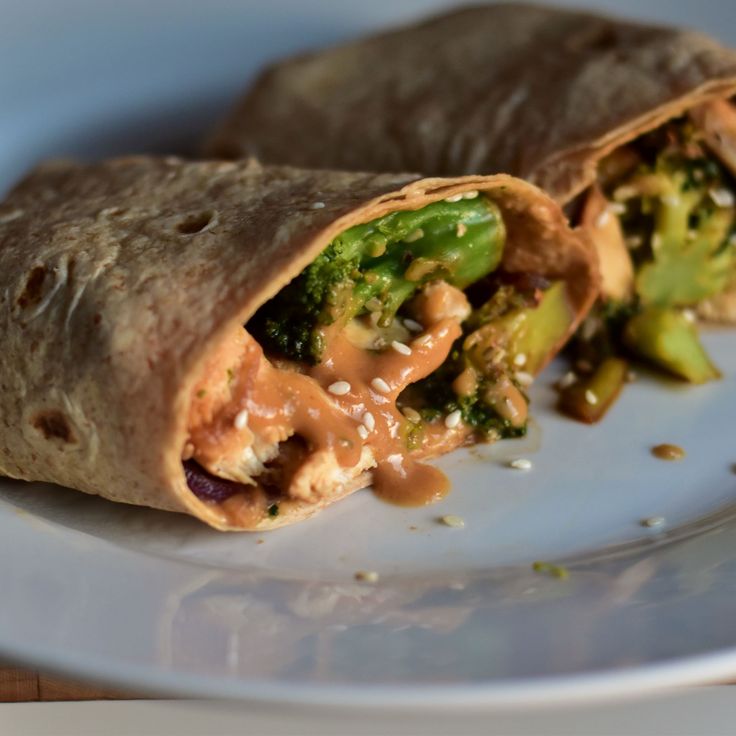 a burrito filled with broccoli and sauce on a plate