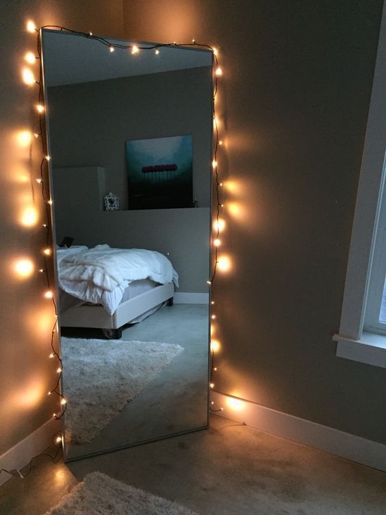 a bedroom with lights on the wall and a large mirror in front of it that is lit up