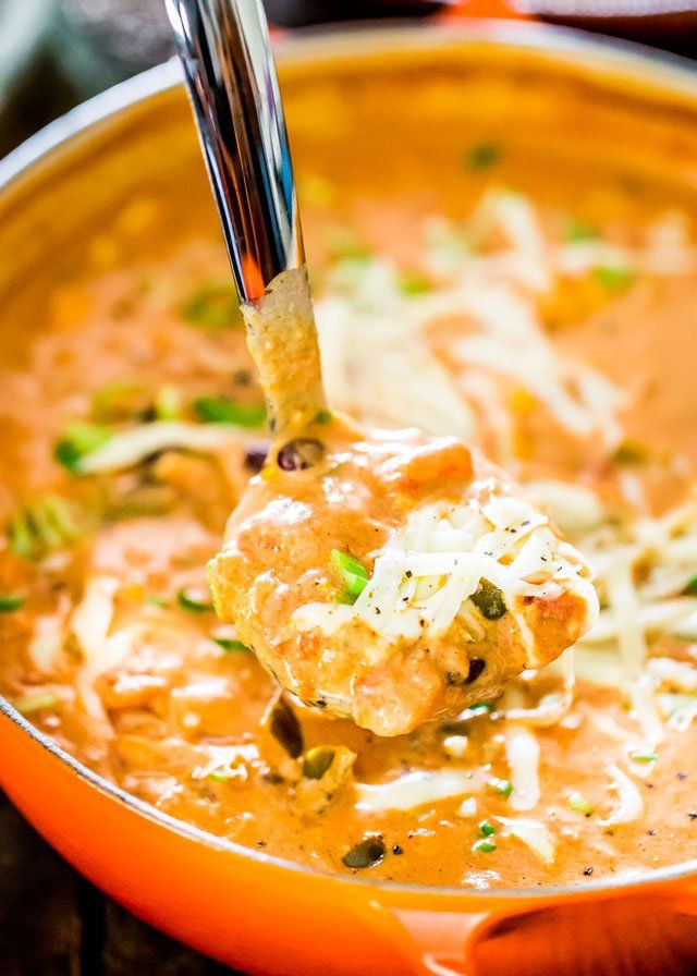 a ladle full of soup with meatballs and parmesan cheese