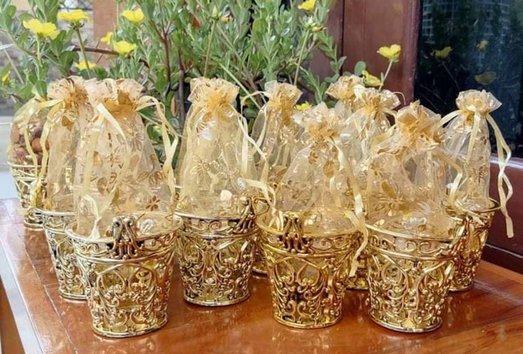 gold colored baskets with bows and ribbons are sitting on a table