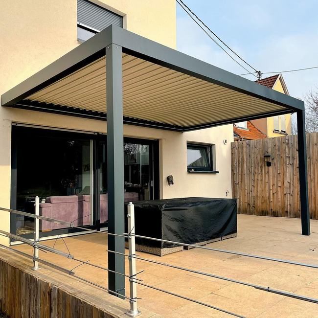 an outdoor covered patio with furniture on the deck and in the background is a house