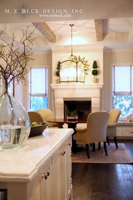 a vase with flowers in it sitting on top of a kitchen counter next to a fireplace