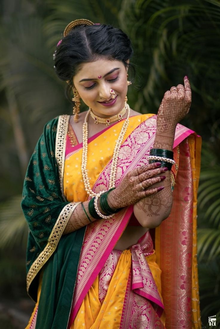 a woman in a yellow and green sari is holding her hands out to the side