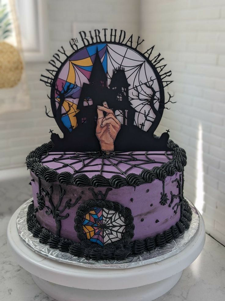 a purple and black birthday cake sitting on top of a table