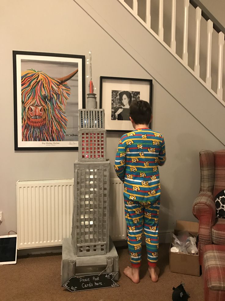 a young boy standing in front of a painting on the wall next to a stair case