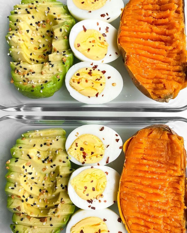 two trays filled with different types of food on top of each other and topped with hard boiled eggs