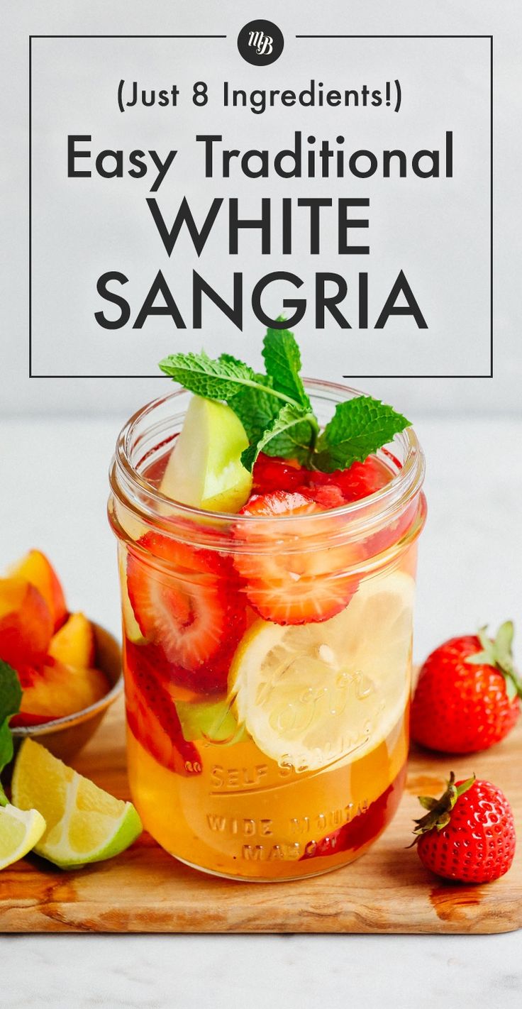 a mason jar filled with sliced strawberries, lemons and mint on top of a cutting board