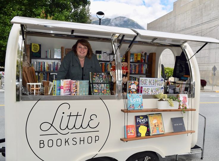 a woman standing behind a little book shop