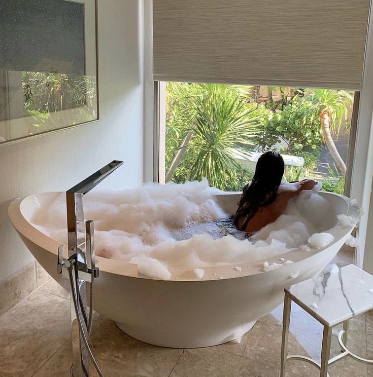 a woman sitting in a bathtub filled with foam