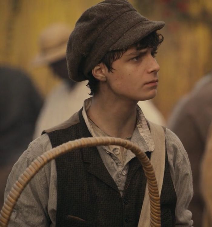 a young man wearing a hat and holding a basket in his hand while standing next to other people