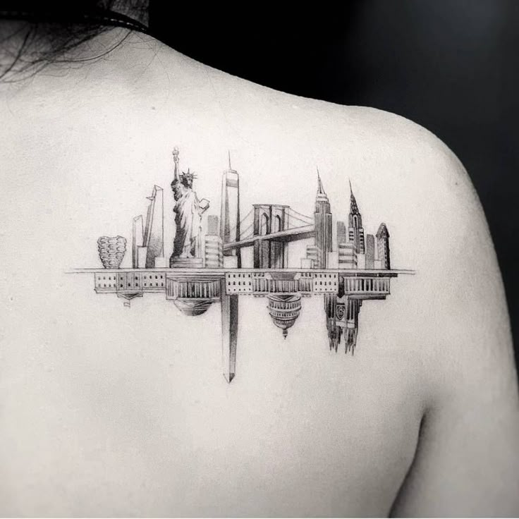 the back of a woman's shoulder with a city skyline tattoo design on it