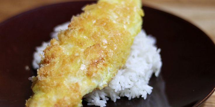 a piece of fried fish on top of white rice in a brown plate with a fork