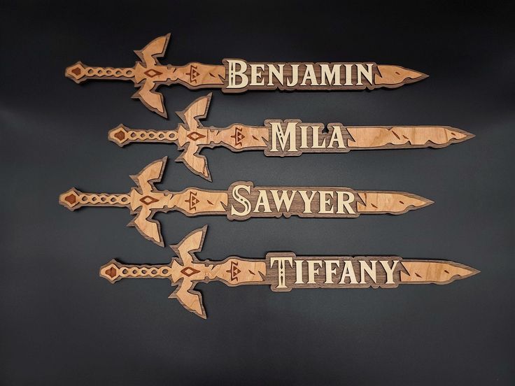 four wooden knives with names on them sitting side by side in front of a black background