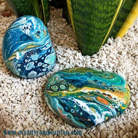 two rocks sitting on top of a pile of gravel next to green planters and plants