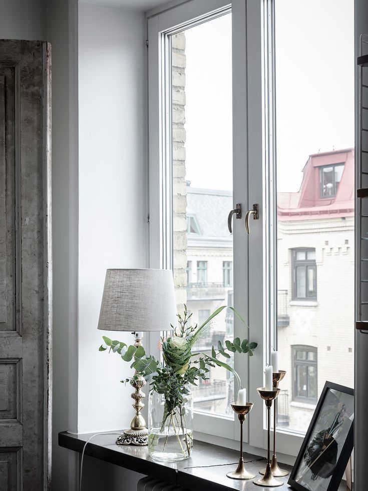 a table with a lamp and vase on it in front of a window