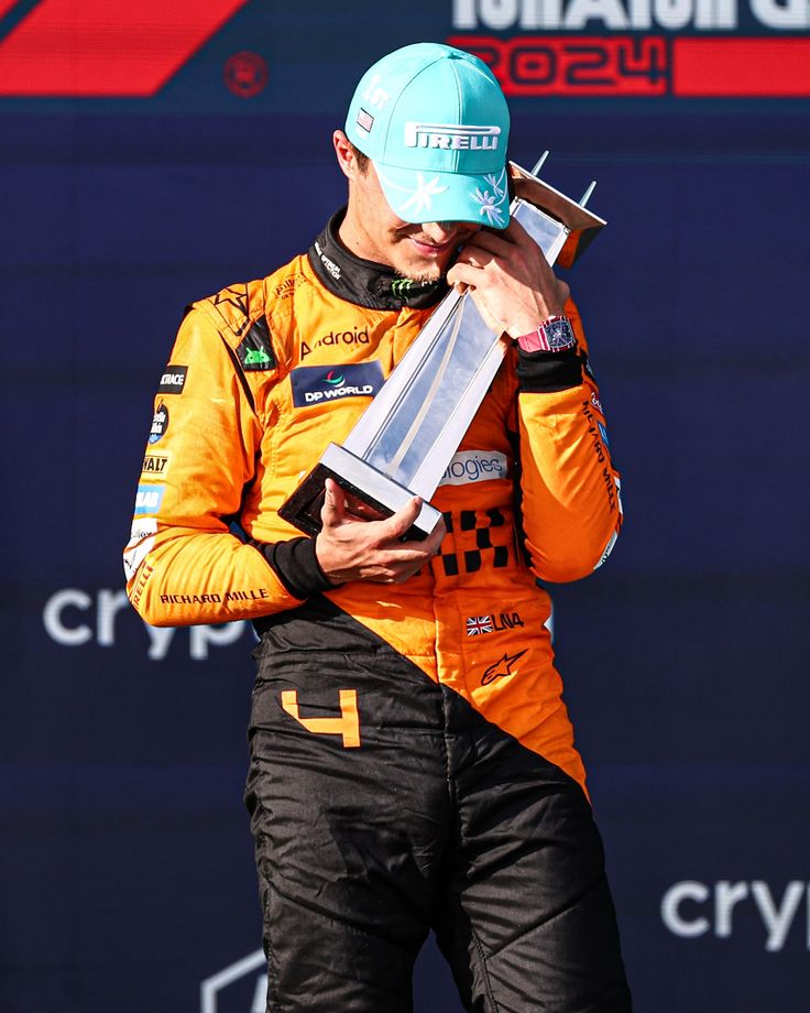 a man in an orange and black outfit holding a trophy on top of his head