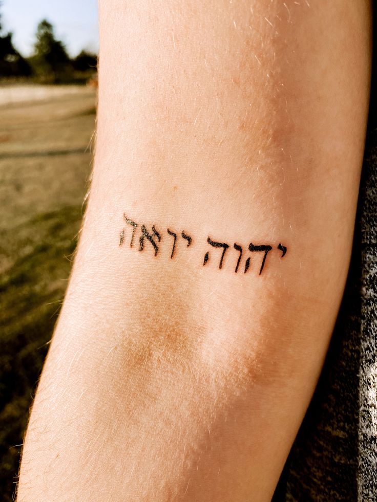 a man's arm with the word hebrew written on it in cursive writing