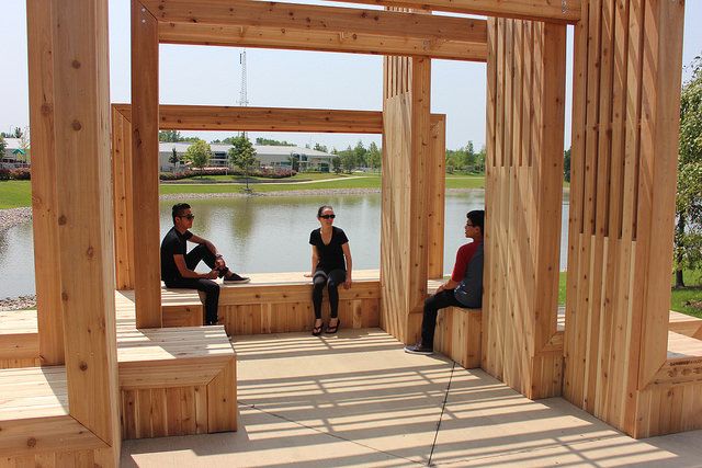 three people sitting on wooden benches in front of a lake