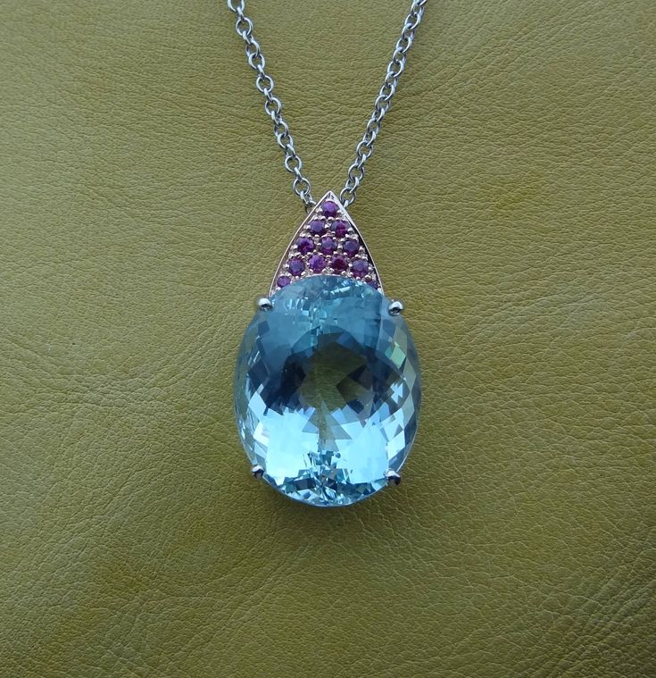 "This handmade one of a kind pendant is made in 14k rose and white gold with a huge fine color natural Aquamarine. The 12 pave set rubies are of fine quality and .36 cts total weight. The 14k white gold chain is included and can be made 16,17 or 18 inch long. We love this pendant because it represents the way jewelry should be made with craftsmanship and quality. This pendant is anything but ordinary. Our pieces are designed and made with craftsmanship and sustainability in mind, our designs are Luxury Oval Cabochon Gemstones, Exquisite Oval Gemstones With Accents, Luxury Oval Cabochon Necklace, Luxury Oval Sapphire Gemstones, Luxury Oval Gemstones, Luxury Pear-shaped Gemstones For Gift, Luxury Hallmarked Jewelry, Oval Luxury Gemstones With Accents, Luxury Oval Gemstones With Accents