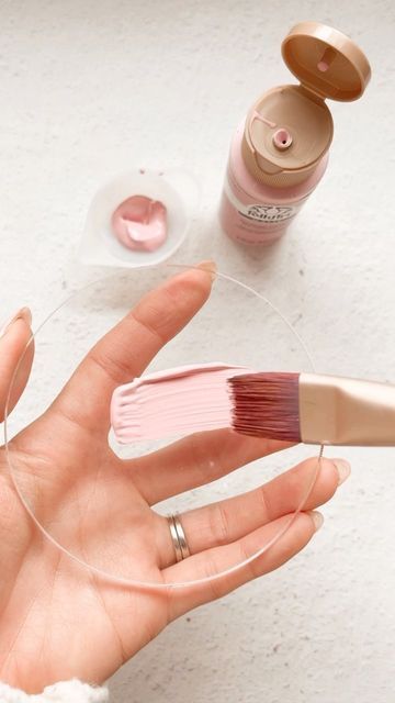 a person's hand holding a pink brush and some other items