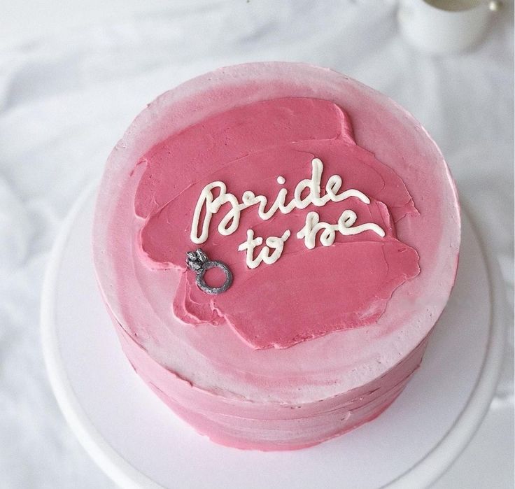 a pink cake with the words bride to be on it sitting on a white plate