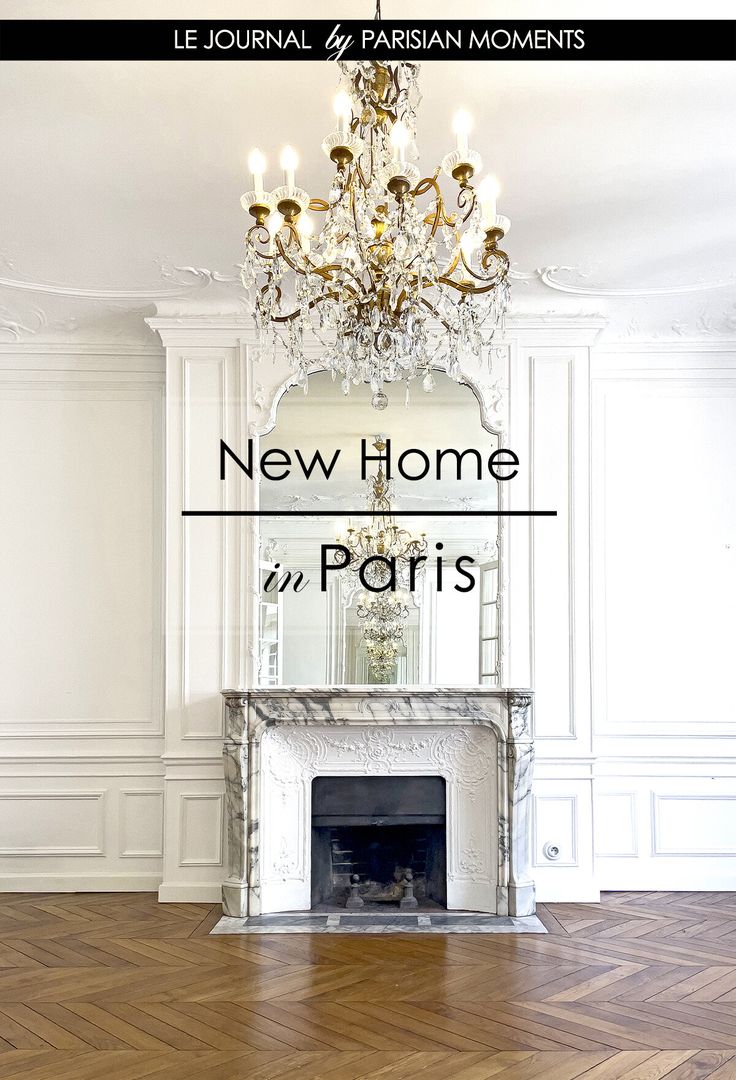 a room with a fireplace and chandelier in the center, next to a white wall