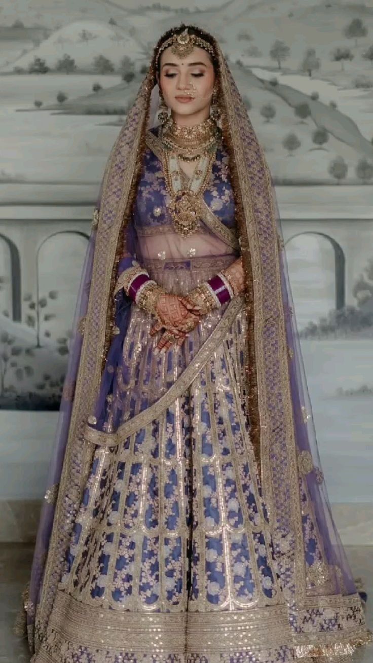 a woman in a blue and gold bridal gown with her hands on her hips