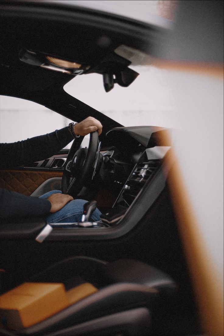 a woman sitting in the driver's seat of a car with her hand on the steering wheel