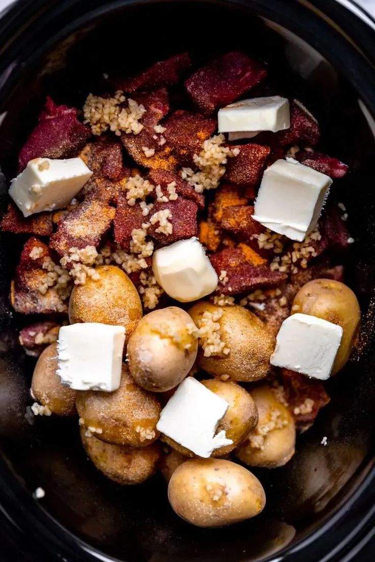 crock pot filled with different types of food including potatoes and meats in it