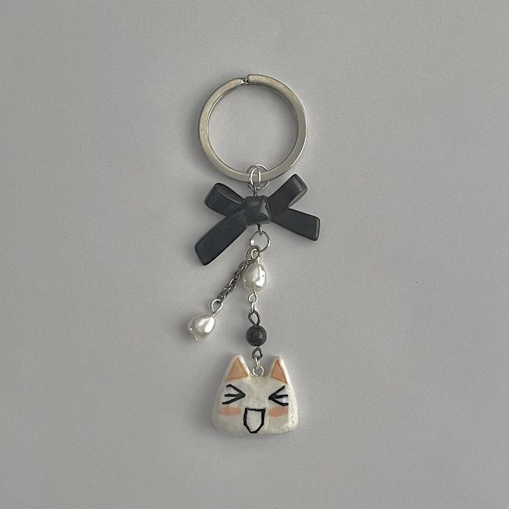 a keychain with a cat face on it and a black ribbon around the neck