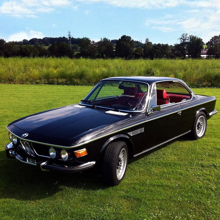 a black car parked on top of a lush green field