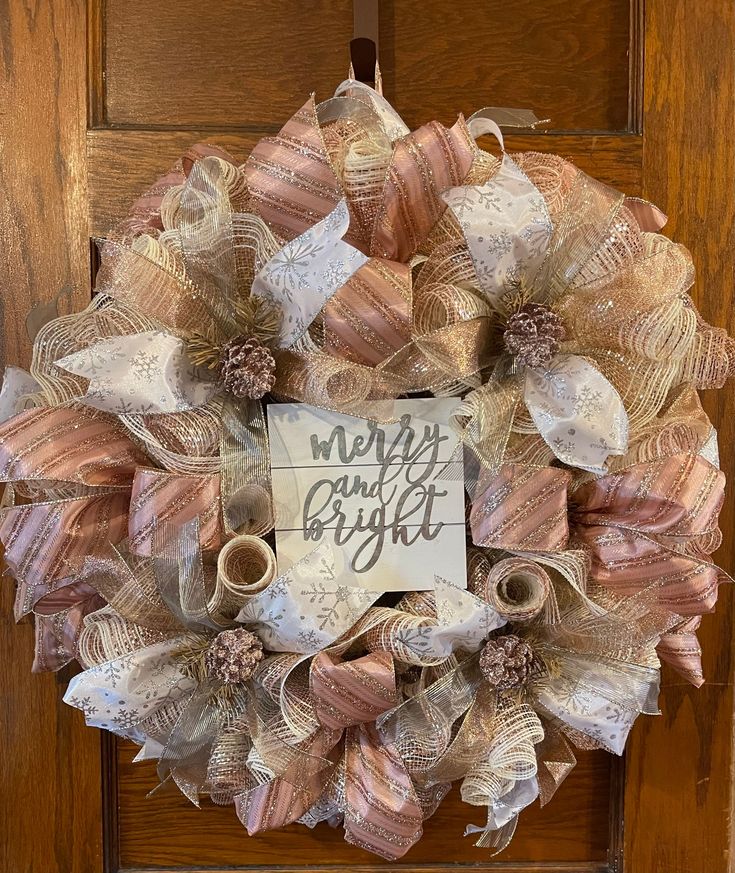 a wreath that has been decorated with ribbon and some words on it, hanging from the front door