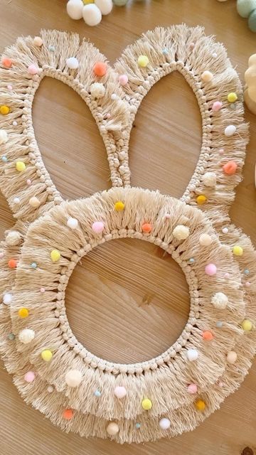 three bunny ears made out of yarn on a wooden table with candy candies around it